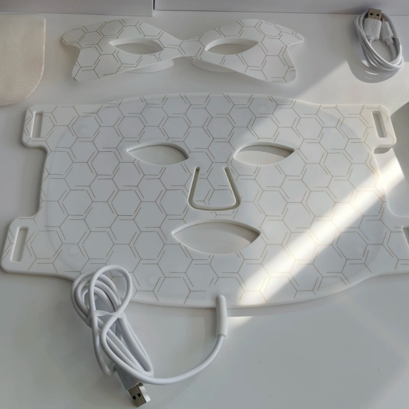 Detail of the white Amporea LED mask silicone surface with gold honeycomb pattern and wired controller cable